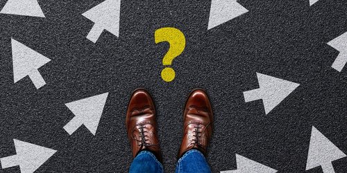 Männer Schuhe auf schwarzem Untergrund mit Pfeilen und einem Fragezeichen
