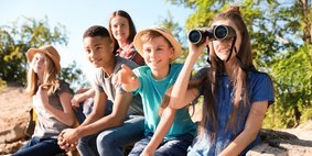 Kinder machen einen Ausflug in die Natur und schauen durch ein Fernglas