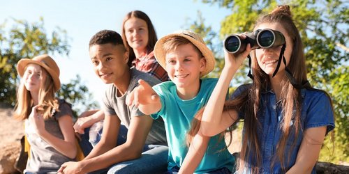 Kinder machen einen Ausflug in die Natur und schauen durch ein Fernglas