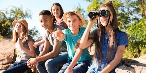 Kinder machen einen Ausflug in die Natur und schauen durch ein Fernglas
