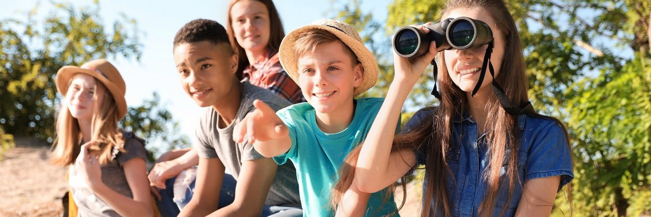 Kinder machen einen Ausflug in die Natur und schauen durch ein Fernglas