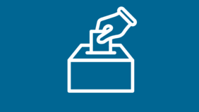 Eine Grafik mit den Worten "Du entscheidest, wer entscheidet" in weißer Schrift auf blauem Hintergrund. Rechts daneben sieht man eine stilisierte Hand, die einen Wahlzettel in eine Wahlurnesteckt. In einem weißen Kasten am oberen Bildrand steht in blauer Schrift "Wahl zur Regionalversammlung am 30. August 2026".