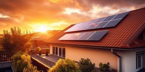 Haus mit Photovoltaikanlage mit Sonneuntergang im Hintergrund