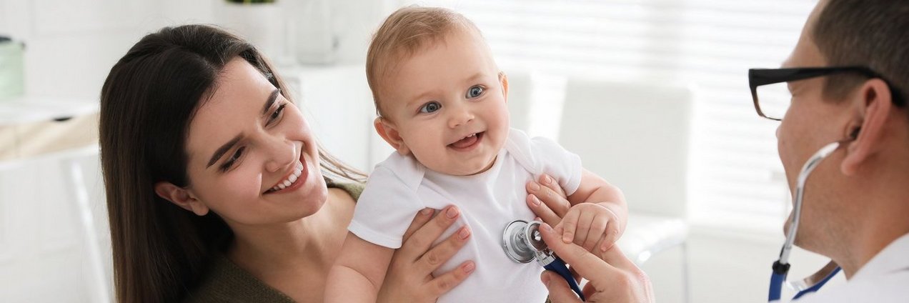 Mutter mit Kind und einem Arzt der das lachende Baby mit einem Stetoskop abhört