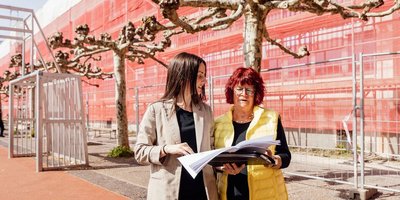 Am Deutsch-Französischen Gymnasium werden neue Fenster eingesetzt und die Fassade umfangreich saniert. Vor Ort konnten sich die Ehrenamtliche Regionalverbandsbeigeordnete Anita Morschette-Sarg (rechts) und Bauamtsmitarbeiterin und zuständige Architektin Savina Madonia-Geyik (links) ein Bild vom Fortschritt der Arbeiten machen.