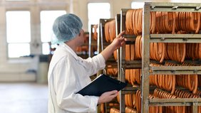 Belehrung im Lebensmittelbereich Mann kontrolliert Bockwürste in Fleischerei