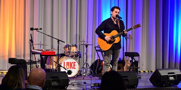 Lukas Schüßler steht mit Gitarre auf der Bühne des Festsaals des Saarbrücker Schlosses, im Hintergrund die Instrumente seiner Bandmitglieder.