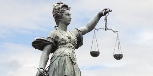 Justitia, Göttin der Gerechtigkeit mit Waage in der linken und Richtschwert in der rechten Hand. 