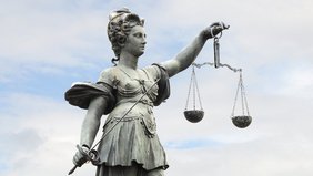 Justitia, Göttin der Gerechtigkeit mit Waage in der linken und Richtschwert in der rechten Hand. 