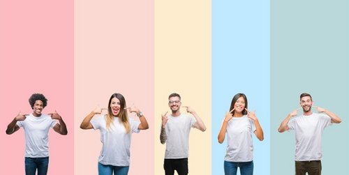 Mehrere junge Menschen, die lächelnd auf ihre Zähne zeigen