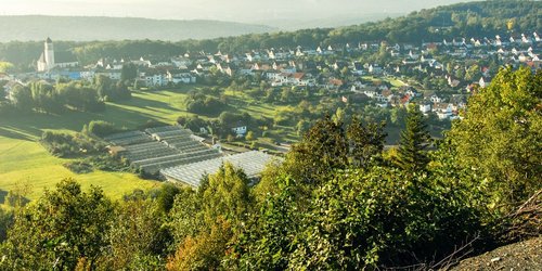 Blick ins Tal mit kleinem Dorf und Gewächshaus.