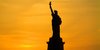 Die New Yorker Freihausstatue vor einem orangen Himmel während des Sonnenuntergangs