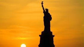 Die New Yorker Freihausstatue vor einem orangen Himmel während des Sonnenuntergangs