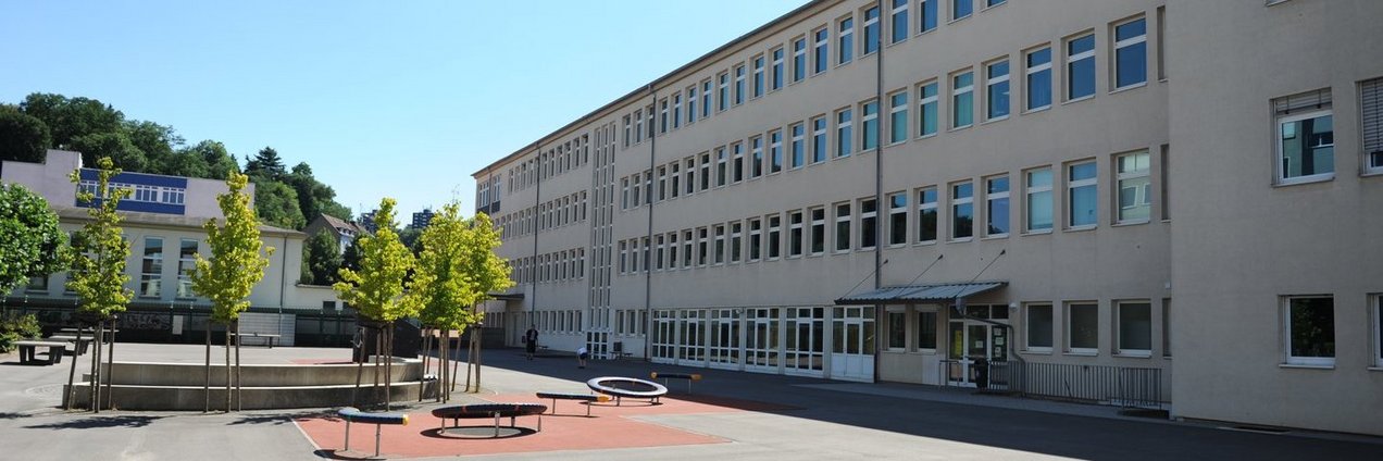 Schulhof mit Trampolin, Bäumen und Tischtennisplatte vor dem Gebäude des Ludwigsgymnasium Saarbrücken
