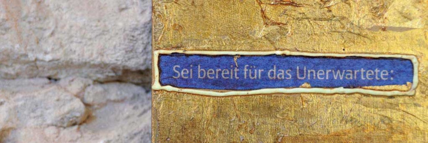 Wand mit Goldenem Element und blauem schild mit Schriftzug