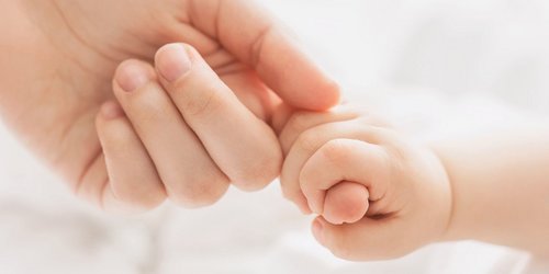 Finger eines Erwachsenen wird von einer Babyhand umschlossen