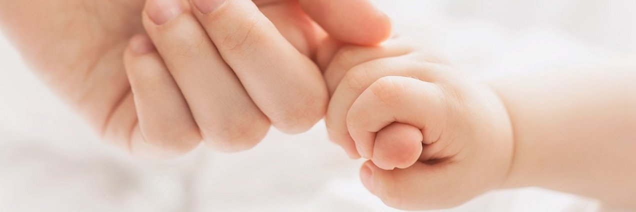 Finger eines Erwachsenen wird von einer Babyhand umschlossen