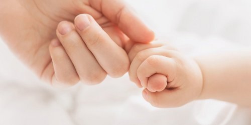 Finger eines Erwachsenen wird von einer Babyhand umschlossen