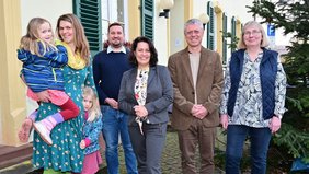 Eine Mutter mit ihren Kindern stehend vor dem Rathaus Kleinblittersdorf. Neben ihr die Regionalverbandsdirektorin, der Bürgermeister und Mitarbeitende des Gesundheitsamtes des Regionalverbands.