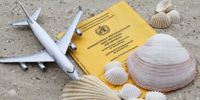 Impfpass am Strand mit Muscheln