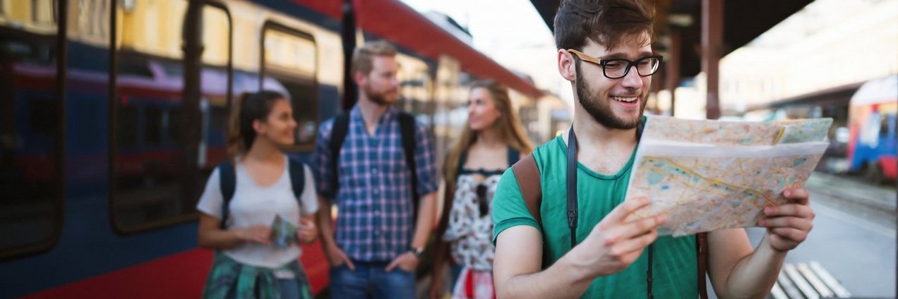 Junger Backpacker am Bahnhof mit Karte in den Händen