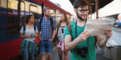 Junger Backpacker am Bahnhof mit Karte in den Händen