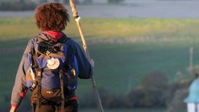Ein Mensch mit Pilgerstab und Rucksack