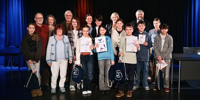Die Teilnehmenden Jungen und Mädchen des Vorlesewettbewerbs stehen gemeinsam mit der Jury und der Regionalverbandsbeigeordneten Anita Morschette-Sarg auf der Bühne im Schlosskeller.