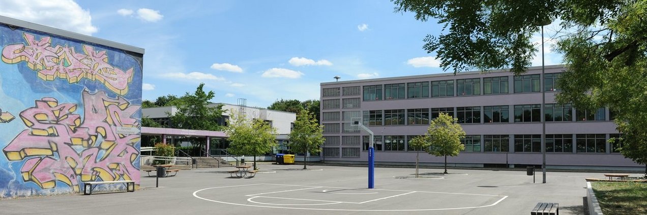 Schulgebäude und Schulhof mit Sport und Spielgeräten