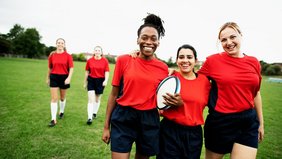 Junge Rugby-Spielerinnen lächeln in die Kamera