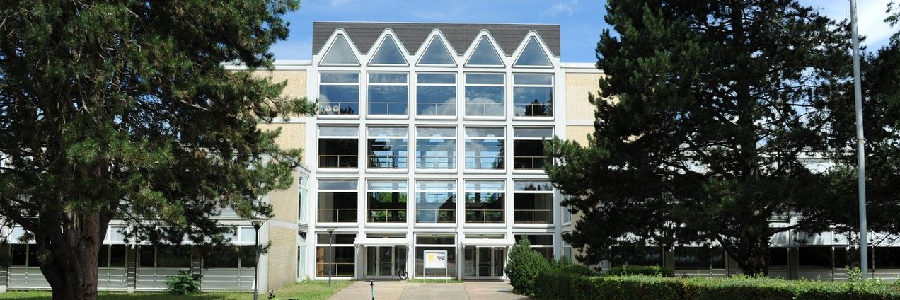 Schulhof mit Bänken und Bäumen vor dem Schulgebäude des Rotenbühl Gymnasium Saarbrücken
