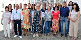 Regionalverbandsdirektor Peter Gillo (3.v..r.) freut sich gemeinsam mit weiteren Vertretern des Regionalverbands-Jugendamtes und der Träger der Freien Jugendhilfe über die Unterzeichnung der langfristigen Kooperationsverträge für die Schulsozialarbeit. Alle haben sich vor dem Saarbrücker Schloss aufgestellt.