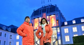 Regionalverbandsdirektorin Dr. Carolin Lehberger und die Frauenbeauftragte des Regionalverbandes, Mirjam Altmeier-Koletzki stehen auf dem Schlossplatz vor dem Saarbrücker Schloss, dessen Festsaal im Mittelbau anlässlich des Internationalen Tages zur Beseitigung von Gewalt an Frauen in orangefarbenem Licht strahlt