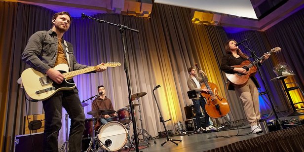 Zum Abschluss präsentierte Isabell Krohn einige Songs mit ihrer Band "The Strangers". Foto: Kerstin Krämer Isabell Krohn tritt gemeinsam mit den drei Mitgliedern ihrer Band "The Strangers" auf der Bühne des Festsaals auf. Die drei Männer spielen Gitarre, Schlagzeug und Bass, Isabell Krohn Gitarre.