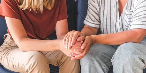 Eine Person hält die Hände einer anderen Person in ihren Händen.