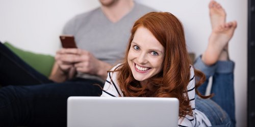 Eine lachende junge frau mit Laptop