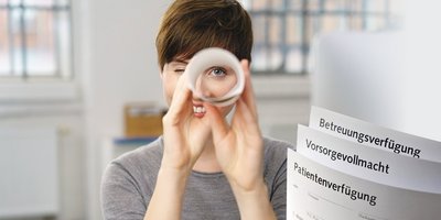 Frau mit Blick durch ein gerolltes Programmheft