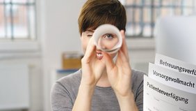 Frau mit Blick durch ein gerolltes Programmheft