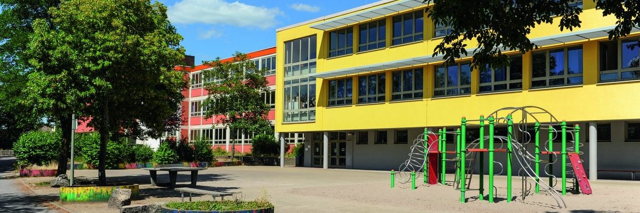 gelbes Schulgebäude mit Schulhof der Gemeinschafsschule Kleinblittersdorf
