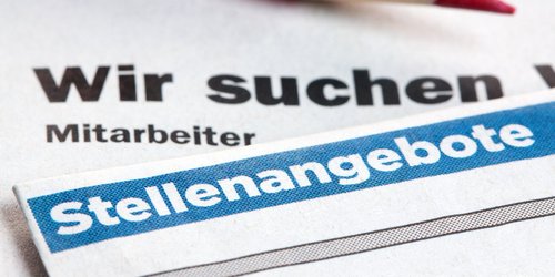 Zeitung mit Inserat Stellenangebote auf welcher ein Rotstift liegt