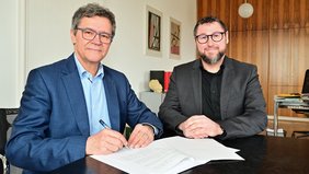 Regionalverbandsdirektor Peter Gillo (l.) und Sven Schäfer, Geschäftsführer der Drogenhilfe Saarbrücken, unterzeichnen gemeinsam die Vereinbarung
