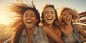 Drei lachend und schreiende Mädchen auf Achterbahn