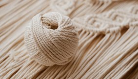 White natural cotton macrame cord in a roll on a handmade wall hanging.
