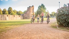 Eine Familie mit zwei Kindern fährt Rad an der Burg Bucherbach in Köllerbach
