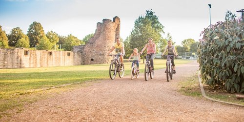 Eine Familie mit zwei Kindern fährt Rad an der Burg Bucherbach in Köllerbach