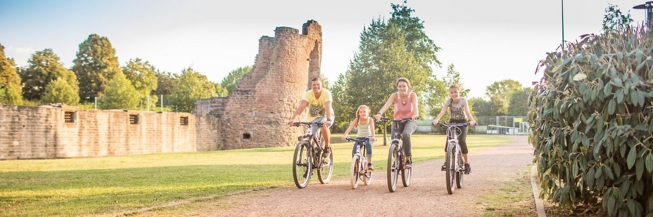 Eine Familie mit zwei Kindern fährt Rad an der Burg Bucherbach in Köllerbach