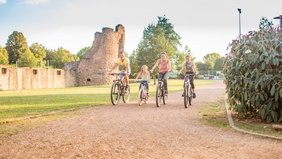 Eine Familie mit zwei Kindern fährt Rad an der Burg Bucherbach in Köllerbach