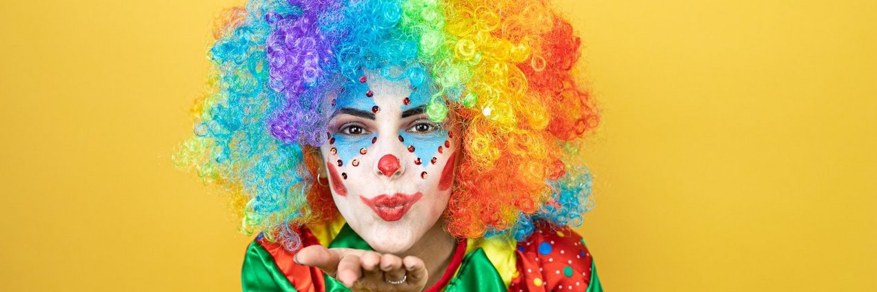 Frau im Clownskostüm macht Kusshand