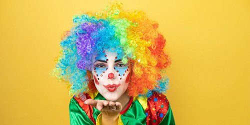 Frau im Clownskostüm macht Kusshand