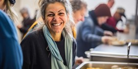 Frau an der Essensausgabe lächelt freundlich in die Kamera.